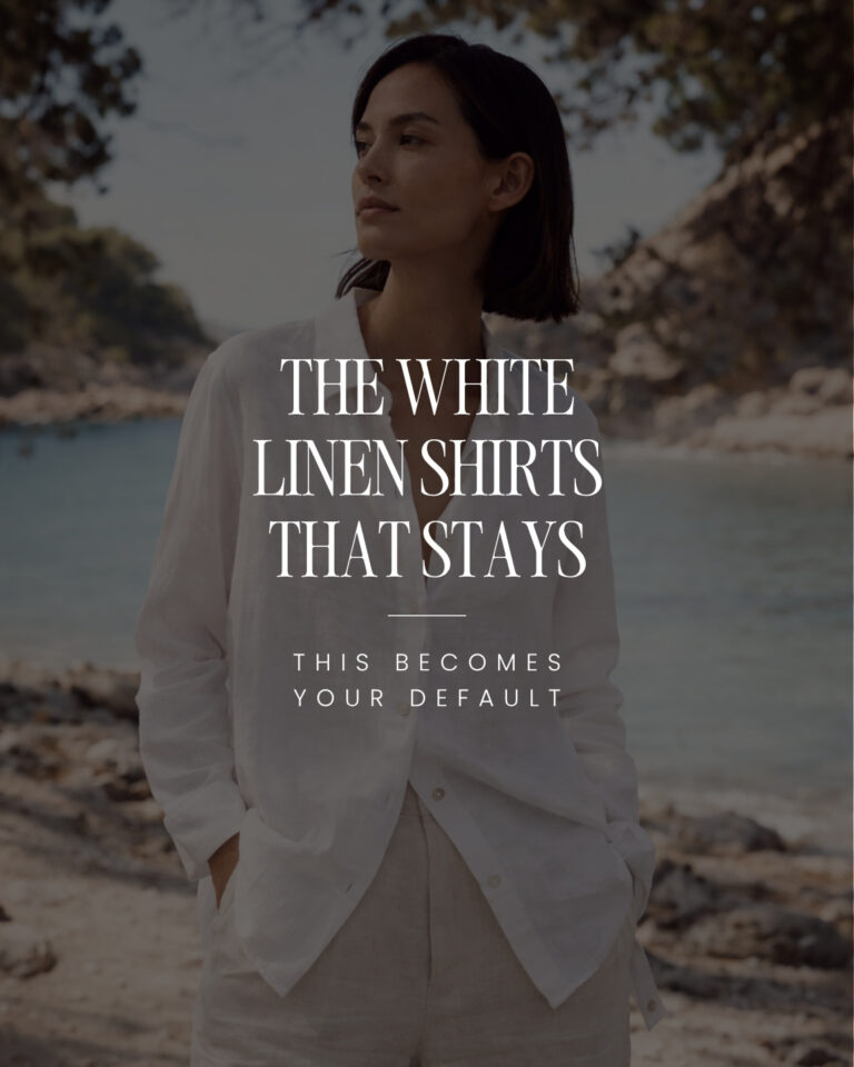 Woman wearing a relaxed white linen shirt and neutral trousers by the sea, styled as part of a minimalist capsule wardrobe.